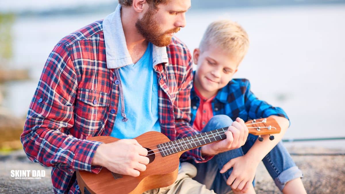 Man and boy playing a ukulele together.