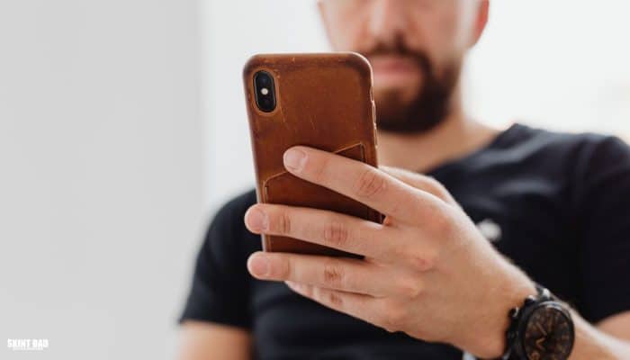 Person looking at their phone while checking their bank transactions at home.