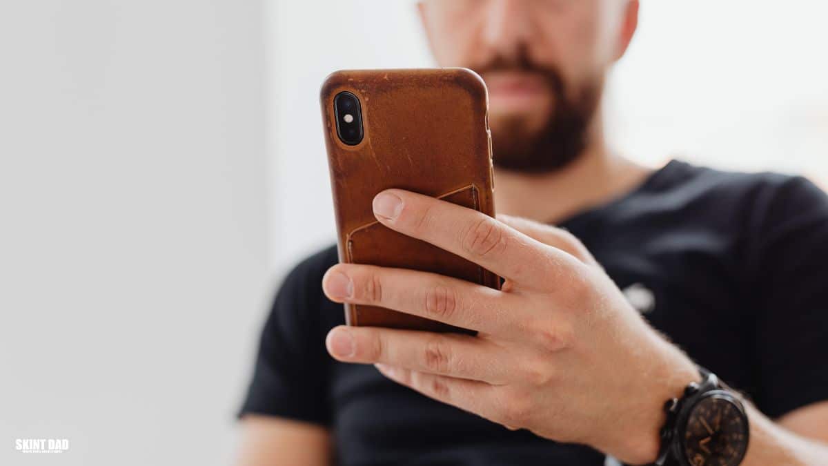 Person looking at their phone while checking their bank transactions at home.