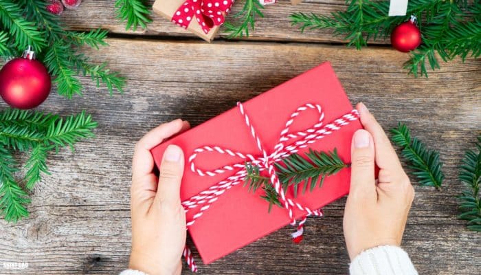 Hands placing a small Christmas kindness bundle on a kitchen table for a struggling family