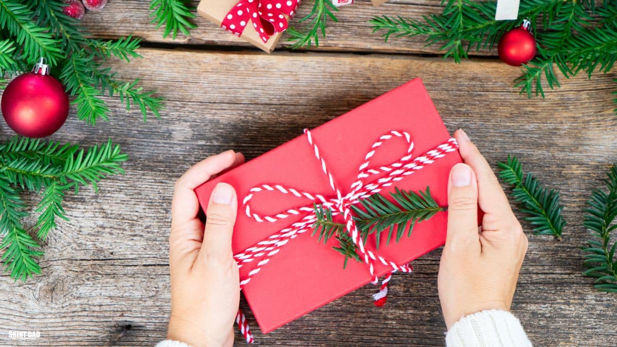 Hands placing a small Christmas kindness bundle on a kitchen table for a struggling family