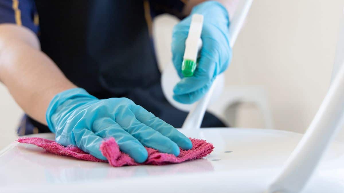 Person cleaning a surface with a cloth and spray bottle