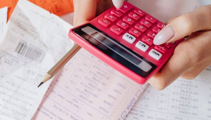 Hands using a calculator alongside paperwork and receipts
