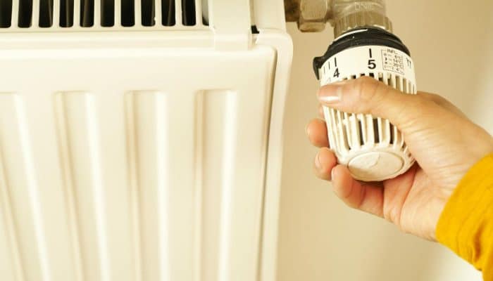 A hand adjusting the temperature control on a radiator.
