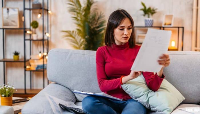 Young woman reading paperwork at home about household finances
