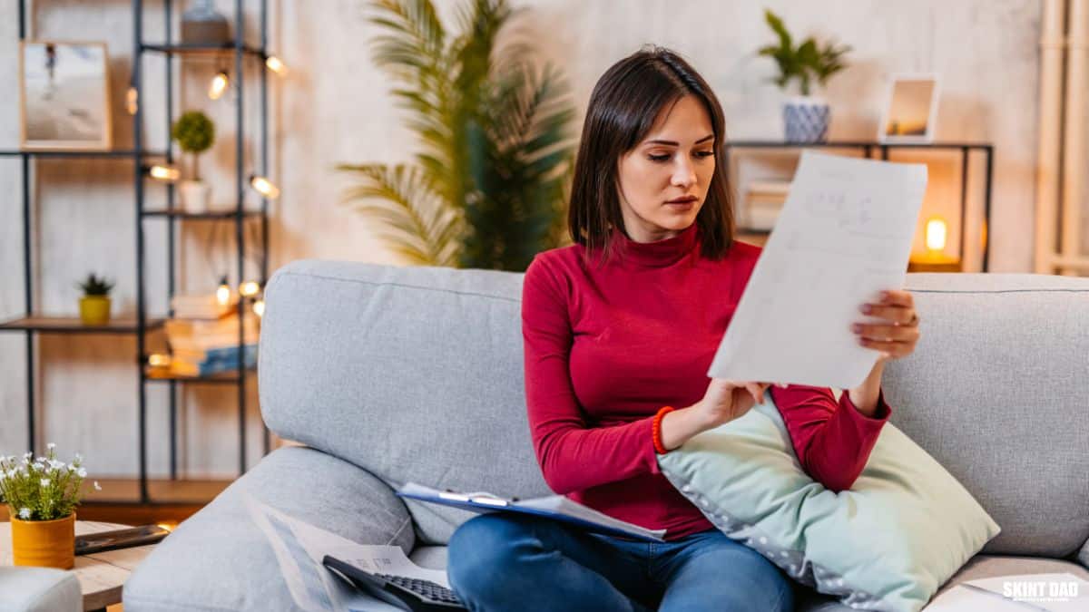 Young woman reading paperwork at home about household finances