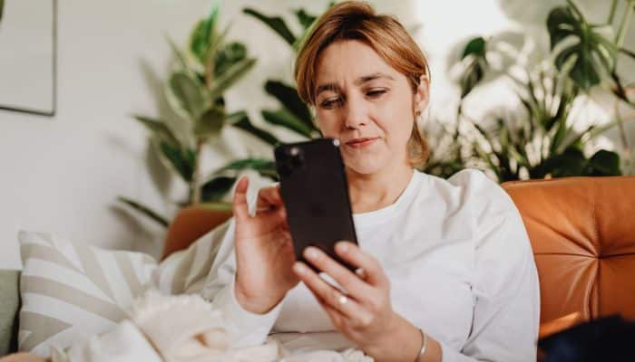 Woman looking at a mobile phone while sitting at home