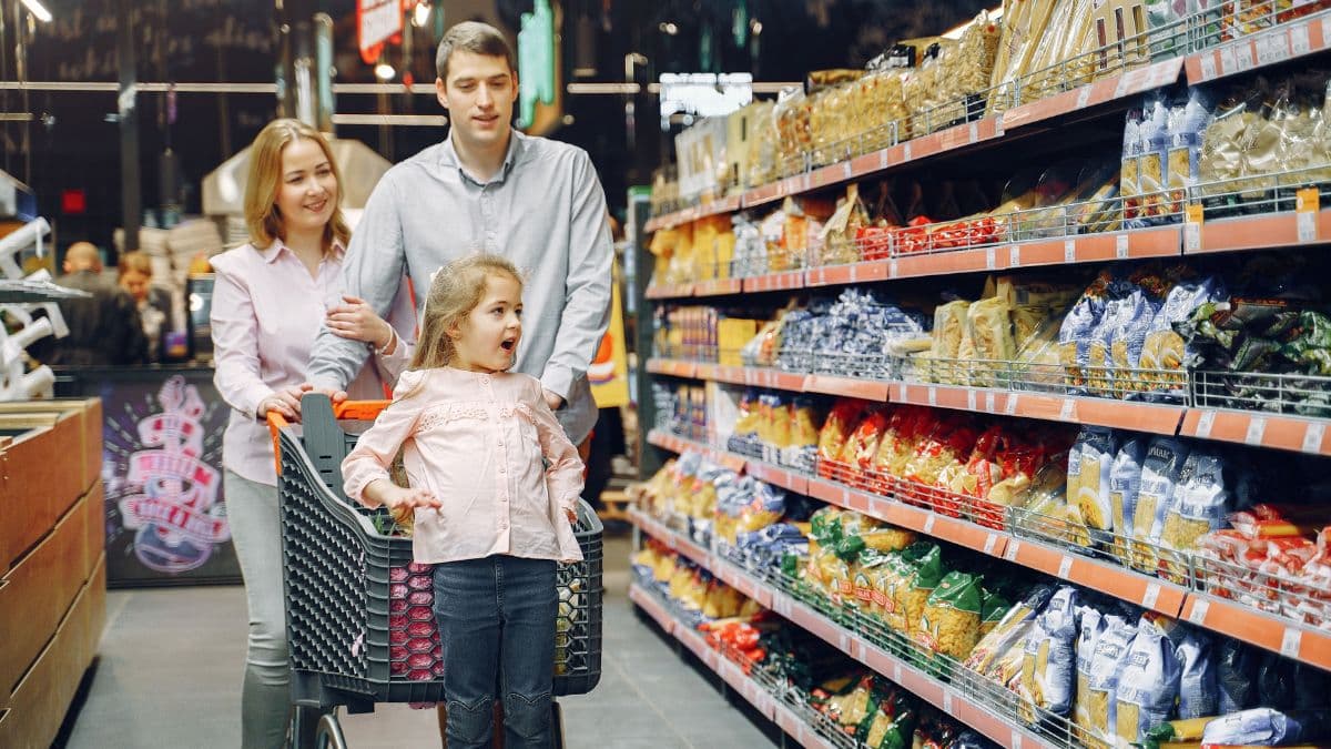 Family shopping together in a supermarket aisle filled with groceries