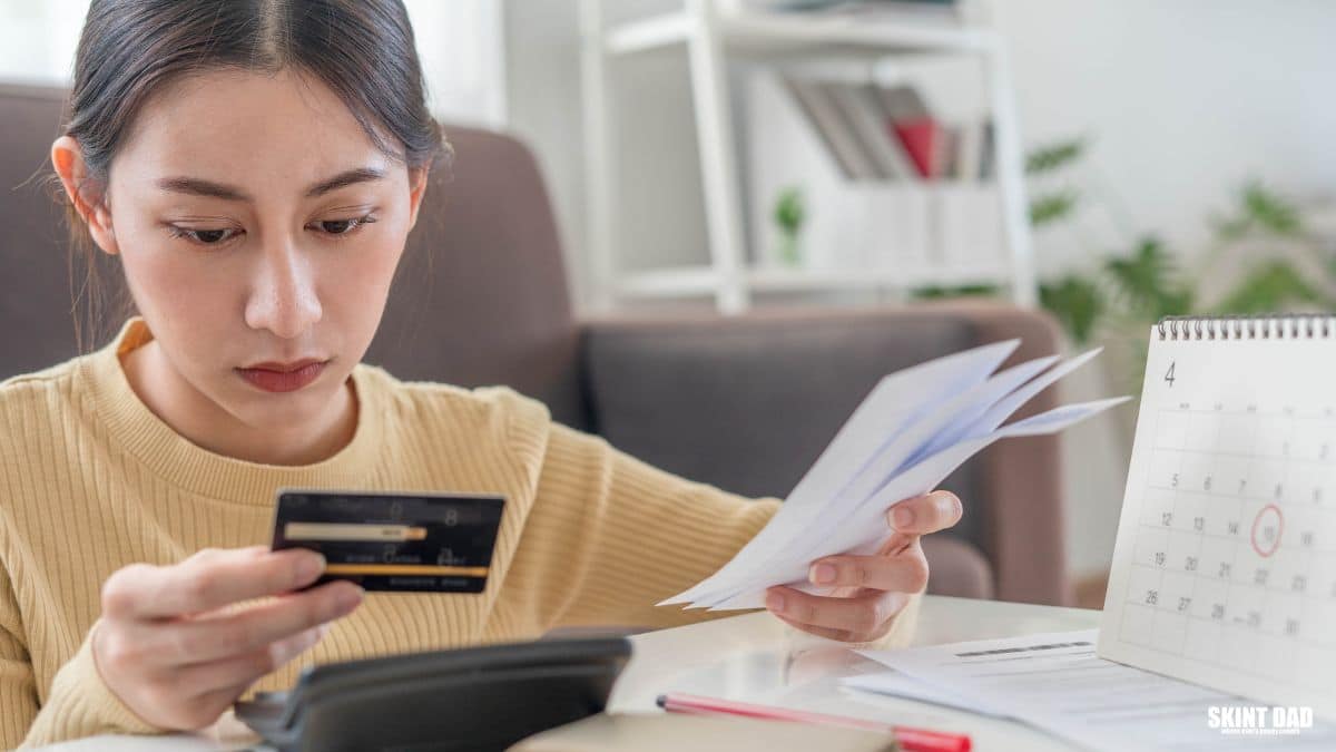 Woman holding a credit card while checking household bills and repayments.