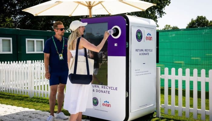 Woman returning an Evian plastic bottle into a reverse vending machine at a Wimbledon Deposit Return Scheme trial