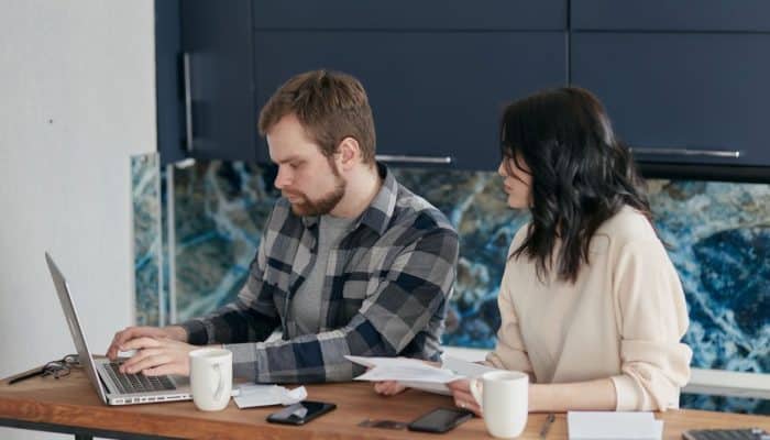 Couple reviewing household bills beside a laptop at home.