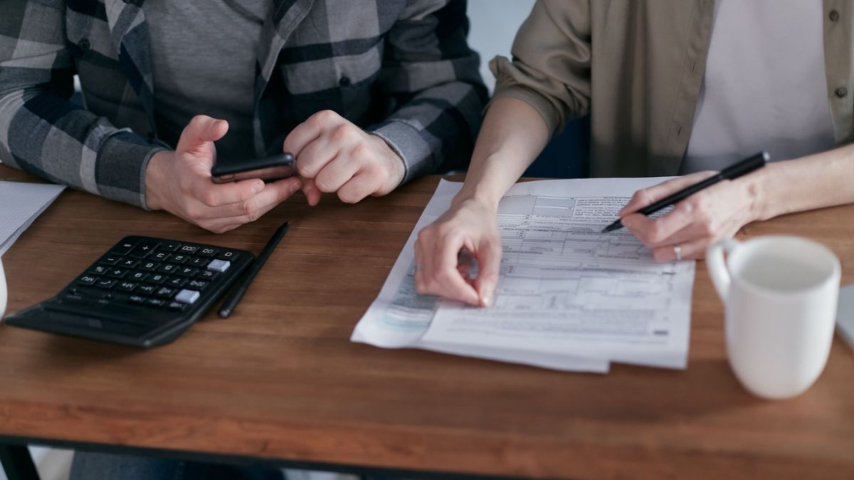 Two people reviewing household bills and paperwork with a calculator