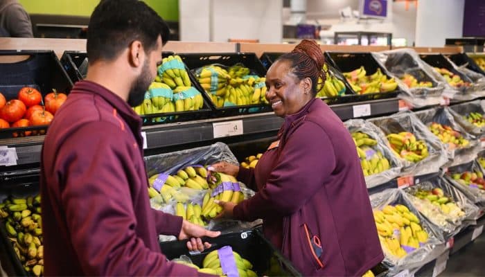 Two Sainsbury’s colleagues working in the fruit and vegetable aisle of a supermarket