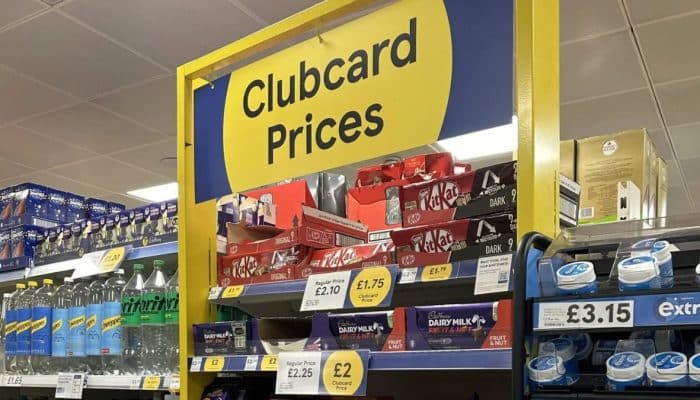 Tesco Clubcard Prices sign above shelves of branded groceries